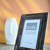 Black Horn Step Design Picture Frame placed on table with warm yellow background and white ceramic vase