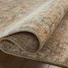 Side view of Heritage Ocean Sand rug curled at one corner on hardwood floor