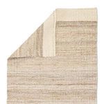 Back side of the jute rug showing tight flat weave and white bordered edge with visible stitching