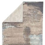 Back side of rug partially folded, revealing light ivory woven underside