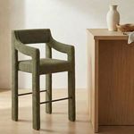 Elise Counter Stool shown in a kitchen setting next to light wood counter with ceramic and wood decor