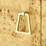 Close-up on one gold trapezoid door handle mounted on burl wood