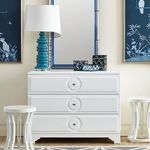 Savoy dresser styled in living room with lamp, mirror, two blue paintings, and white side stools