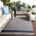 Blue and beige striped rug styled on patio with wicker sofa, cushions, and green plants