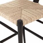 Close-up of woven seat corner wrapped around black teak stool leg