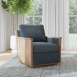 Norman Swivel Accent Chair styled in bright room with large windows, rug, and green plant