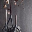 Three cast iron candle holders with tall candles on textured stone blocks under floating dried leaves