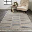 Beckett rug placed on dark wood floor next to beige tufted armchair and small table with decor