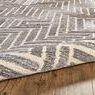 Side angle with rug slightly rolled, highlighting pile thickness and soft texture on wood flooring