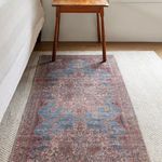 Rug placed under wooden table on layered neutral carpets, showing medallion pattern in room setting