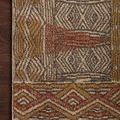 Close-up of rug corner laying on dark wooden floor emphasizing geometric border and pile density