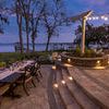 Monterey Dining Chairs around outdoor dining table at lakeside patio at dusk with string lights