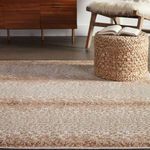 Rug shown in room with woven pouf and mid-century chair accented by neutral walls