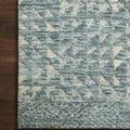 Close-up of rug corner on dark wood floor highlighting detailed geometric pattern and texture