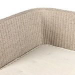 Close-up of the banquette’s inner corner with woven rattan back and seat cushion tufting