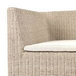 Close-up side view focusing on rattan weave and cushion layering at armrest