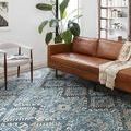 Rug shown in living room setting with brown leather sofa and white chair