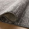 Rolled edge close-up showing the rug’s thickness and binding on wood floor