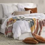 quilt layered with multi-color patterned throw blanket and styled with assorted brown and beige pillows