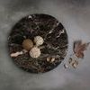 Brown Emperador round tray styled on gray surface holding decorative natural pods and seeds with dried leaf beside