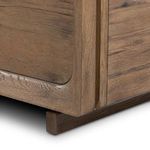 Close-up detail of rounded nightstand corner and wood texture at base with leg visible