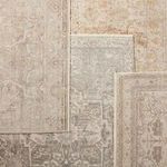 Multiple vintage style rugs layered, with middle rug featuring the Alain Medallion pattern in gray and cream