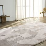 Angled view of rug laid out in sunlit room with sheer white curtains and light wood flooring