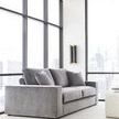 Wide room perspective showing sofa angled near floor-to-ceiling windows with urban skyline backdrop