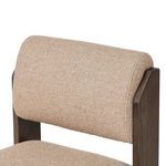 Close-up of upper backrest upholstery with visible fabric stitching and framed by dark wood