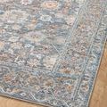 Diagonal view of rug on wood floor focusing on intricate floral and geometric border