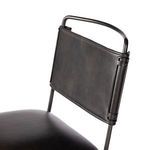 Close-up of Wharton chair upper backrest showing matte black iron tubing and leather cushion texture
