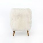 Close-up of armchair corner highlighting wooden arm, thick fur upholstery, and tapered leg