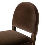 Close-up on the curved velvet backrest and cushioned seat joint with dark wooden frame