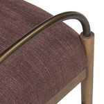Close-up of bronze curved arm resting in wooden leg joint over purple upholstery