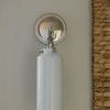 Back view of sconce showing polished round backplate and cylindrical opaque glass shade