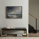 Framed painting hung above black bench in modern neutral room with stair railing visible