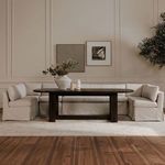 Dining banquette arranged around a dark wood table in a softly lit styled room with wall art