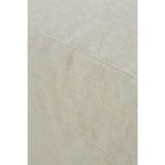 Diagonal side close-up focusing on slipcover ottoman's fabric seams and corner slit
