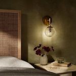 Sunset Sconce illuminated on bedroom wall above nightstand with vase and books
