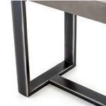 Close-up on rectangular open-frame design of dark iron base under grey concrete top