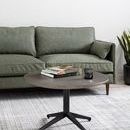 Sofa featured in a room with white walls, plants, and a round coffee table with books and candle