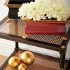 Close-up of Conner Cane End Table top and shelf with decorative gold and black vases and white flowers