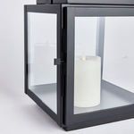 Detail view of the lantern's glass door and hinge with candle visible inside