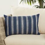 lumbar pillow styled on cream outdoor sofa with woven wicker frame and green plant background