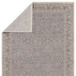 Back side view of rug folded at one corner revealing light beige backing fabric