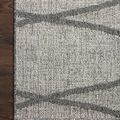 Corner of Rainier Dove Grey Rug laying flat on dark wood floor emphasizing pattern meeting at edge