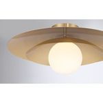 Installed ceiling light showing warm brass finish and softly glowing white opal globe in room context