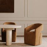 Barrow chair in dining room setting next to rounded stone dining table and neutral decor