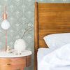 Wallpaper shown as bedroom accent wall behind wooden headboard with side table, lamp, and white bedding