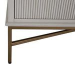 Detail of satin brass metal leg with geometric crossbar support under chest corner